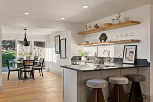 Kitchen featuring kitchen peninsula, light hardwood / wood-style floors, a kitchen bar, and hanging light fixtures