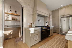 Kitchen featuring cream cabinets, light wood-type flooring, premium range hood, and high quality appliances