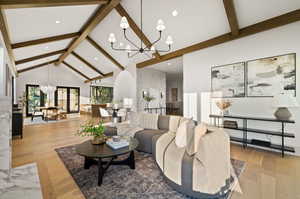 Living room featuring light hardwood / wood-style floors, high vaulted ceiling, a chandelier, and beamed ceiling