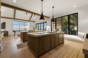 Kitchen featuring a kitchen island with sink, hardwood / wood-style flooring, sink, vaulted ceiling with beams, and decorative light fixtures