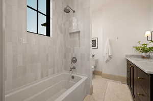 Full bathroom featuring tiled shower / bath, vanity, toilet, and tile patterned floors