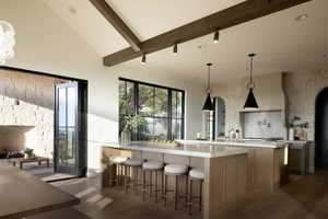 Kitchen featuring hardwood / wood-style flooring, a breakfast bar area, backsplash, hanging light fixtures, and a kitchen island with sink