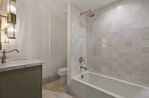 Full bathroom with toilet, vanity, and tiled shower / bath