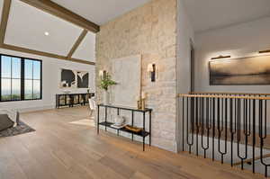 Hallway with vaulted ceiling with beams and hardwood / wood-style flooring