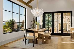 Dining area featuring high vaulted ceiling, plenty of natural light, a chandelier, and light hardwood / wood-style flooring