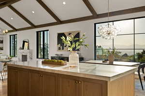 Kitchen featuring vaulted ceiling with beams, a fireplace, a chandelier, and decorative light fixtures