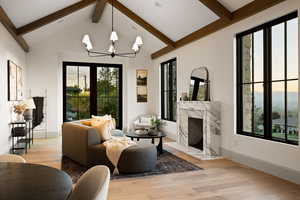 Living room featuring plenty of natural light, a premium fireplace, beam ceiling, and light hardwood / wood-style flooring