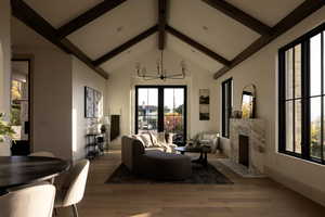 Living room with wood-type flooring, a chandelier, high vaulted ceiling, beamed ceiling, and a fireplace