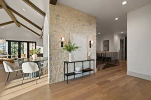 Hallway with light wood-type flooring, high vaulted ceiling, beamed ceiling, french doors, and a notable chandelier