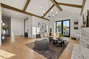 Living room featuring a chandelier, high vaulted ceiling, light hardwood / wood-style flooring, and beamed ceiling