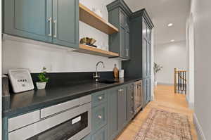 Kitchen with light wood-type flooring, wine cooler, and sink