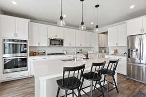 Stainless steel double oven, five burner stove, with oversized quartz island with breakfast bar. Cabinetry is soft close.