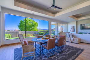 Dining area featuring a raised ceiling, wood-type flooring, and ceiling fan