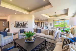 Living room with ceiling fan and a raised ceiling