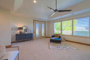 Living area featuring light carpet, a healthy amount of sunlight, ceiling fan, and a tray ceiling