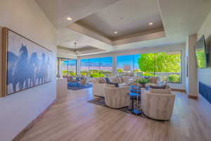 Living room featuring a tray ceiling, light hardwood / wood-style flooring, and ceiling fan