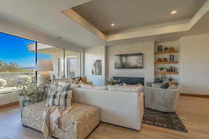 Living room featuring a tray ceiling, light hardwood / wood-style floors, and a tile fireplace