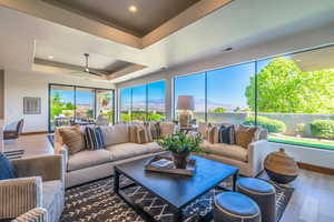 Sunroom with a tray ceiling, a mountain view, and ceiling fan