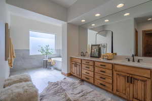 Bathroom with a bathtub, tile patterned floors, tile walls, and vanity