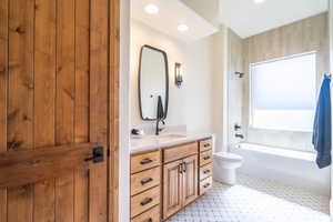 Full bathroom with toilet, vanity, and tiled shower / bath combo