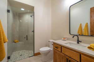 Bathroom with vanity, tile patterned flooring, toilet, and a shower with shower door