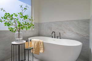 Bathroom featuring tile walls and a washtub