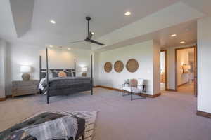 Bedroom featuring ceiling fan, a tray ceiling, and light colored carpet