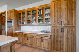 Kitchen featuring stainless steel microwave, light wood-type flooring, and decorative backsplash