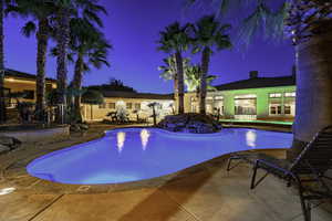 Pool at night featuring a patio area