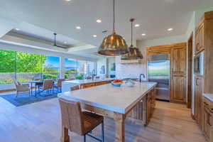 Kitchen featuring light hardwood / wood-style floors, a tray ceiling, a large island, and built in appliances