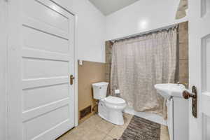 Bathroom with tile patterned floors, a shower with curtain, and toilet