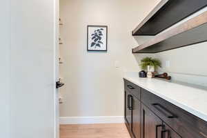 Bar with dark brown cabinetry and light wood-type flooring