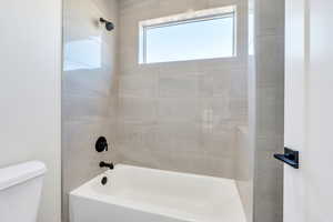 Bathroom featuring toilet and tiled shower / bath combo