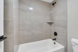 Bathroom featuring toilet and tiled shower / bath combo