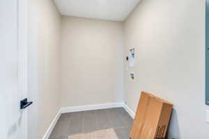 Laundry area featuring hookup for a washing machine, dark tile patterned flooring, and electric dryer hookup