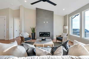 Living room featuring vaulted ceiling, ceiling fan, light hardwood / wood-style floors, and a tile fireplace