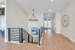 Stairs featuring french doors, a notable chandelier, and wood-type flooring