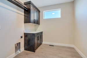 Washroom with cabinets, light hardwood / wood-style floors, and electric dryer hookup