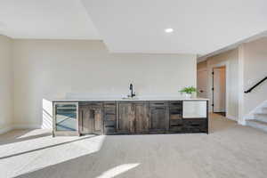 Bar with sink, beverage cooler, and light carpet