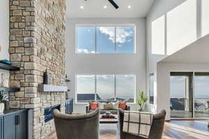 Living room with ceiling fan, a wealth of natural light, hardwood / wood-style flooring, and a stone fireplace