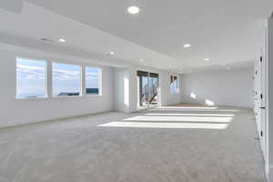 Unfurnished room with light carpet, a healthy amount of sunlight, and a textured ceiling