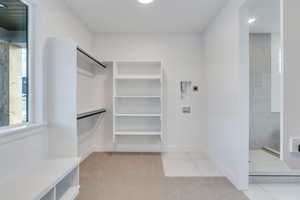 Walk in closet featuring light tile patterned floors and a baseboard radiator