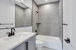 Full bathroom featuring toilet, tiled shower / bath combo, and vanity