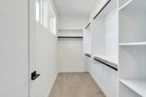 Spacious closet featuring light colored carpet