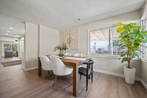 Dining area with a textured ceiling and light hardwood / wood-style flooring