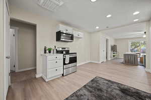 Kitchen featuring ceiling fan, white cabinets, a textured ceiling, light hardwood / wood-style flooring, and appliances with stainless steel finishes