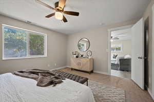 Bedroom featuring a textured ceiling, light carpet, multiple windows, and ceiling fan