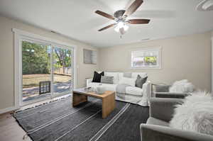 Living room featuring plenty of natural light, wood-type flooring, and ceiling fan