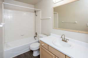 Full bathroom featuring tiled shower / bath combo, hardwood / wood-style flooring, vanity, and toilet