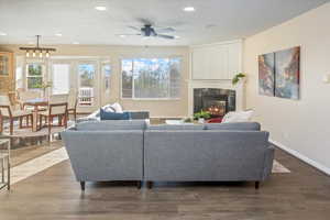 Living room with ceiling fan, dark wood-type flooring, and fireplace